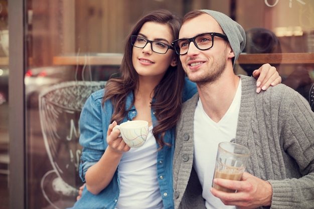 Junges Modepaar, das Kaffee außerhalb des Cafés trinkt