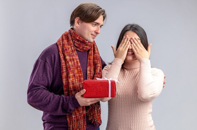 Junges Paar am Valentinstag freut sich über einen Mann, der dem Mädchen eine Geschenkbox gibt, die auf weißem Hintergrund isoliert ist
