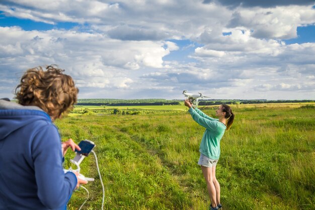 Junges Paar auf einem Feld startet die Drohne in den Himmel