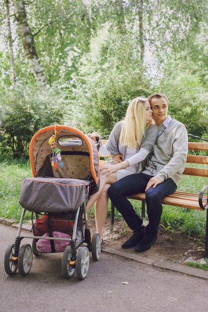 Junges Paar auf einer Bank mit einem Baby Wagen sitzen in einem Park neben