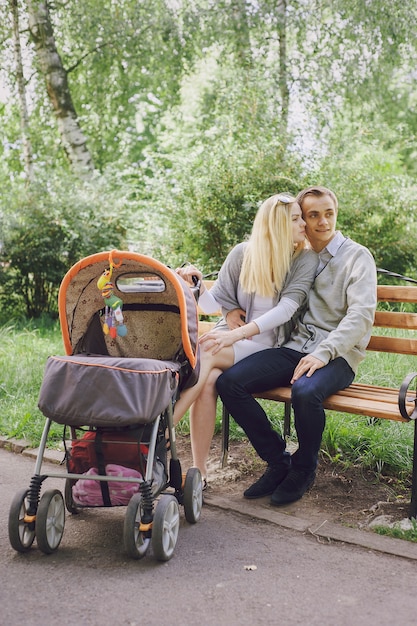 Junges Paar auf einer Bank mit einem Baby Wagen sitzen in einem Park neben