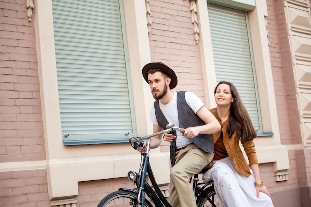 Junges Paar, das auf einem Fahrrad gegen die Wand sitzt