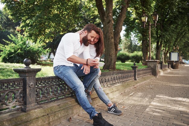 Junges Paar, das ein Smartphone an einem sonnigen Tag in der Stadt betrachtet