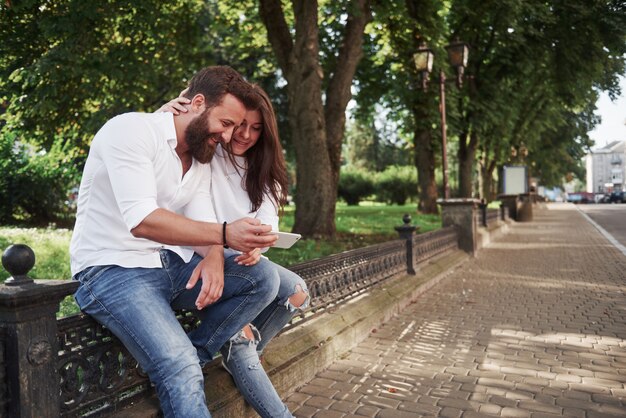 Junges Paar, das ein Smartphone an einem sonnigen Tag in der Stadt betrachtet