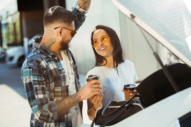 Junges Paar, das für Urlaubsreise auf dem Auto am sonnigen Tag vorbereitet