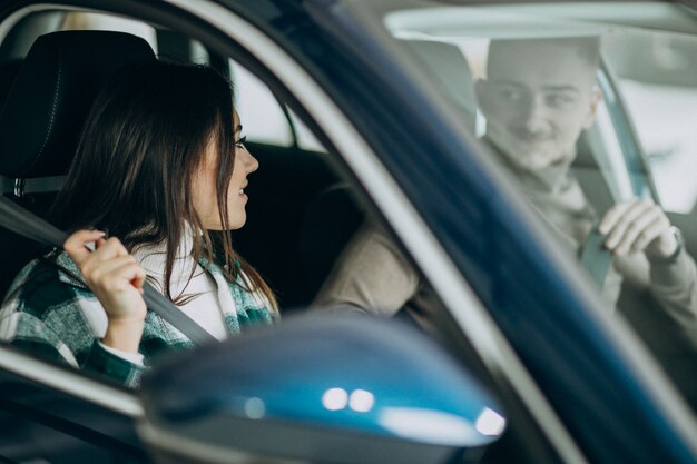 Junges Paar, das im Auto in einem Autoausstellungsraum sitzt