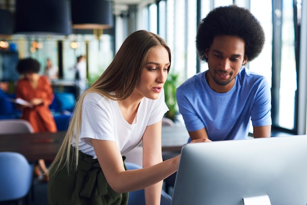 Junges Paar, das im Büro mit Technologie arbeitet