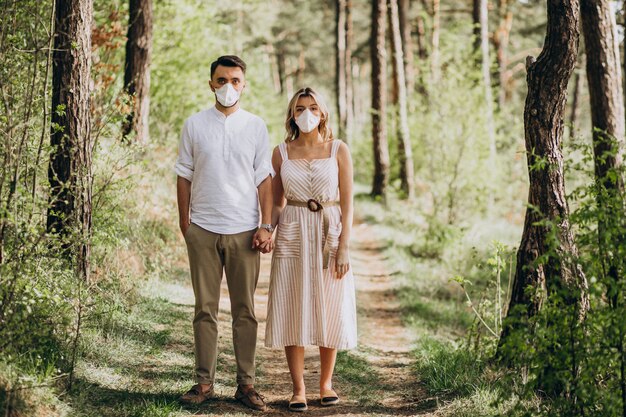 Junges Paar, das Masken zusammen im Wald trägt