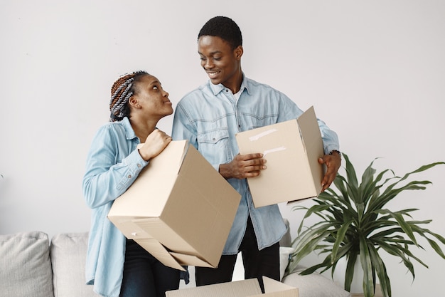 Junges Paar, das zusammen in ein neues Zuhause einzieht. Afroamerikanerpaar mit Pappkartons.