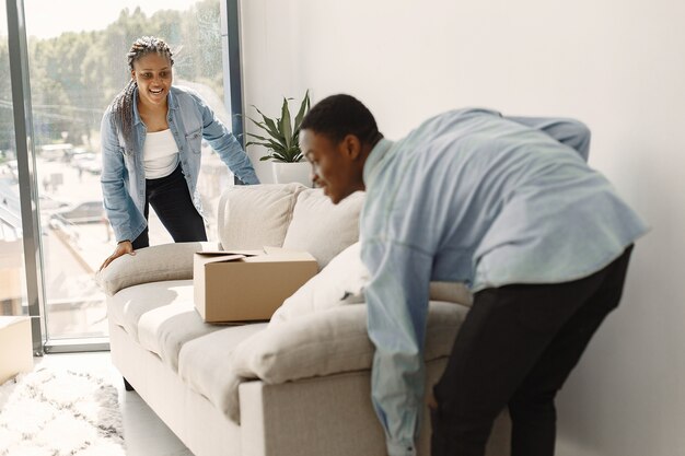 Junges Paar, das zusammen in ein neues Zuhause einzieht. Afroamerikanerpaar mit Pappkartons.