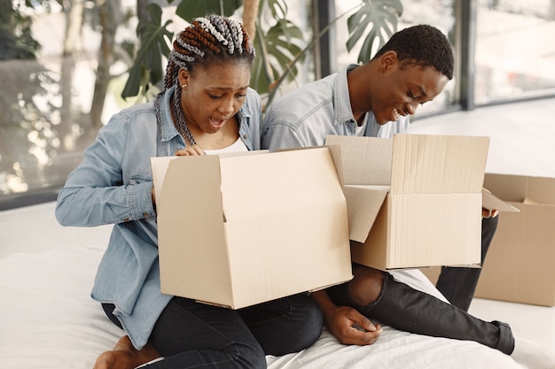 Junges Paar, das zusammen in ein neues Zuhause einzieht. Afroamerikanerpaar mit Pappkartons.