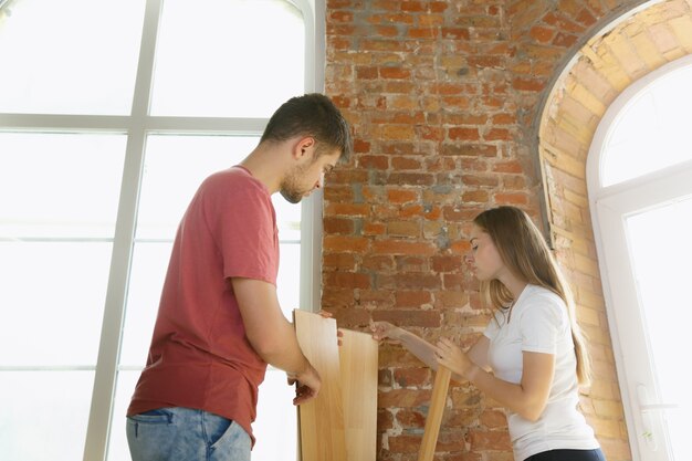 Junges Paar, das zusammen Wohnungsreparatur macht. Verheirateter Mann und Frau machen Renovierung oder Renovierung
