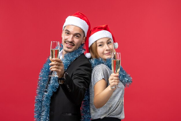 Junges Paar der Vorderansicht, das gerade neues Jahr auf der roten Wand feiert, liebt Weihnachten