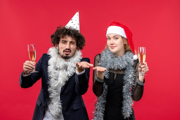 Junges Paar der Vorderansicht, das gerade neues Jahr auf der Weihnachtsfeier der roten Wandliebe feiert