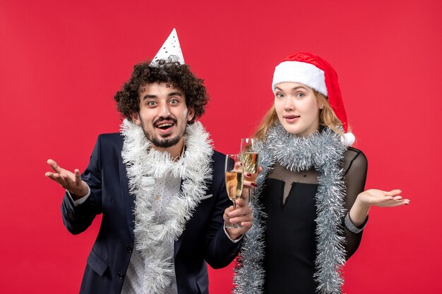 Junges Paar der Vorderansicht, das gerade neues Jahr auf Weihnachtsliebe der roten Wand feiert