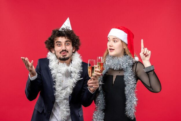 Junges Paar der Vorderansicht, das gerade neues Jahr auf Weihnachtsliebe des roten Wandfotos feiert