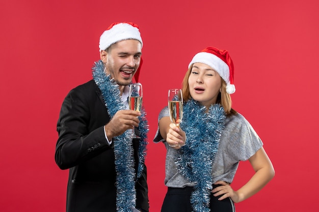 Kostenloses Foto junges paar der vorderansicht, das gerade neues jahr auf weihnachtsliebe-party der roten wand feiert