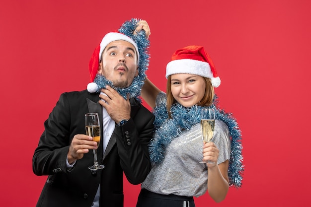 Kostenloses Foto junges paar der vorderansicht, das neues jahr auf rotem boden liebt, liebt weihnachtsfeiergetränk