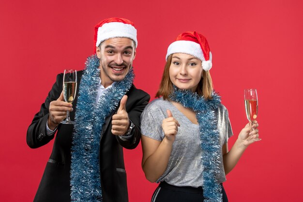 Junges Paar der Vorderansicht, das neues Jahr auf rotem Boden liebt, liebt Weihnachtsfeiergetränk