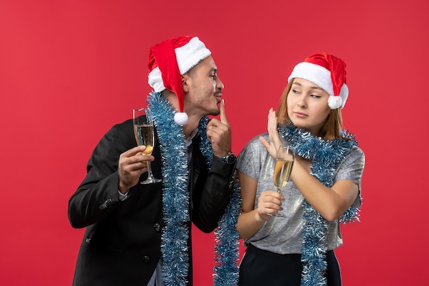 Junges Paar der Vorderansicht, das neues Jahr auf rotem Schreibtisch liebt, liebt Weihnachtsfarbe