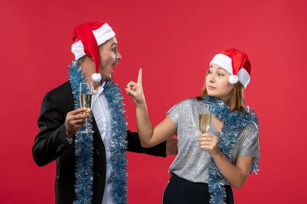 Junges Paar der Vorderansicht, das neues Jahr auf roten Wandliebesweihnachtsfarben feiert