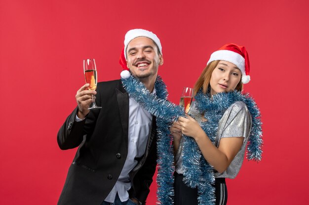 Junges Paar der Vorderansicht, das neues Jahr auf roter Wand liebt, liebt Weihnachtsfarbe