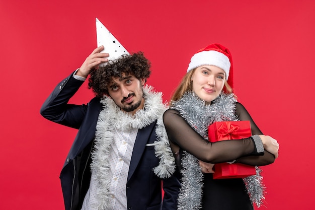 Junges Paar der Vorderansicht, das neues Jahr auf Weihnachtsliebe der roten Wand feiert