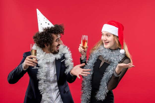 Kostenloses Foto junges paar der vorderansicht, das neues jahr auf weihnachtsliebe der roten wandfeiertage feiert