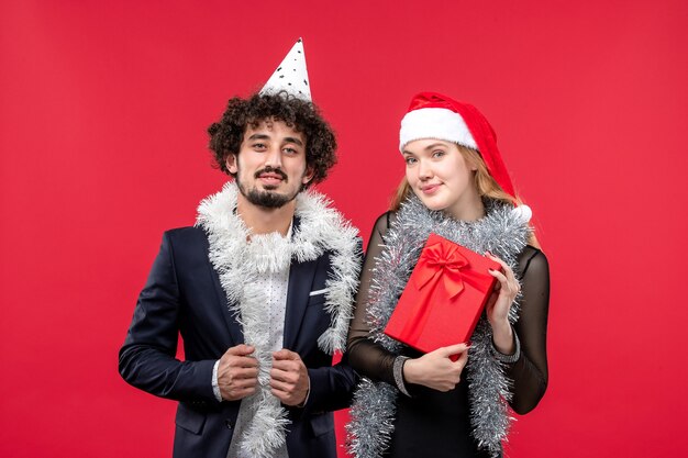 Junges Paar der Vorderansicht, das neues Jahr auf Weihnachtsliebefeiertag der roten Wand feiert