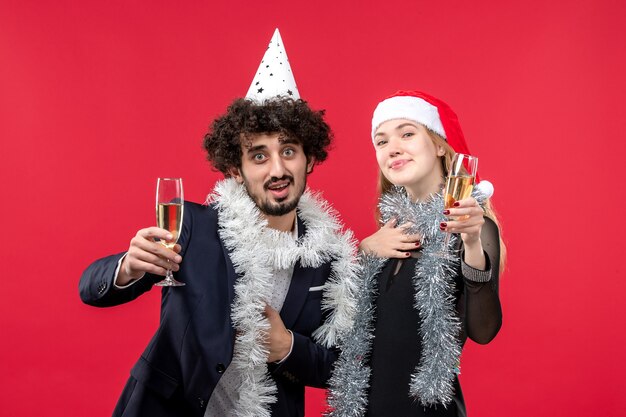 Junges Paar der Vorderansicht, das neues Jahr auf Weihnachtsliebefeiertag der roten Wand feiert