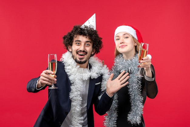 Junges Paar der Vorderansicht, das neues Jahr auf Weihnachtsliebesferien der roten Wand feiert