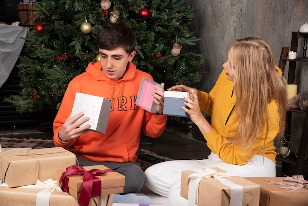 Junges Paar feiert Weihnachten zu Hause mit Geschenken.