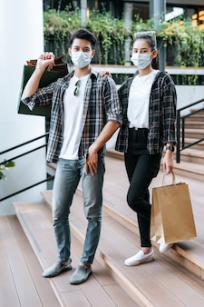 Junges paar in schutzmaske mit mehreren papiereinkaufstüten