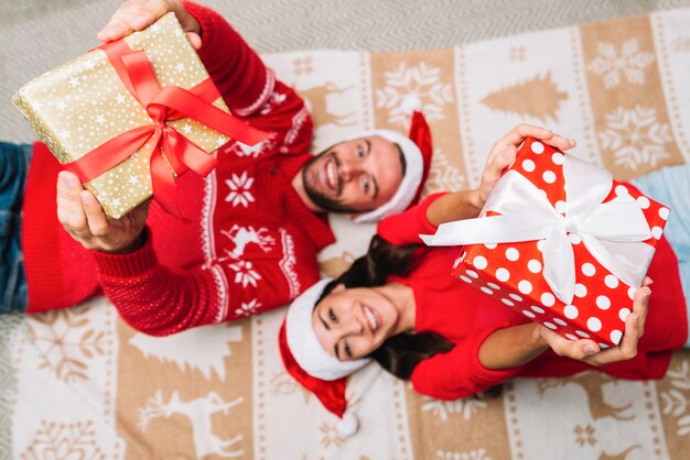 Junges Paar in Weihnachtshüten mit Geschenkboxen