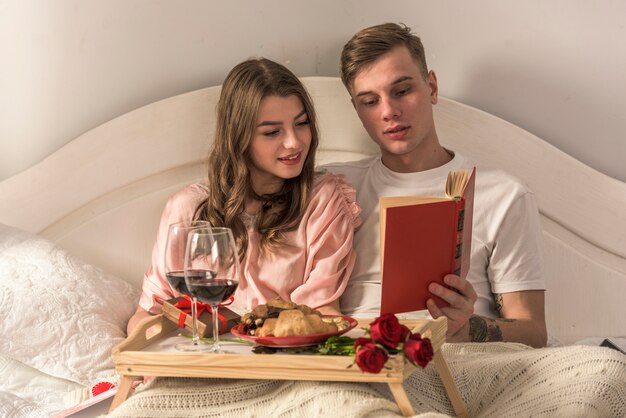 Junges Paar Lesebuch im weißen Bett