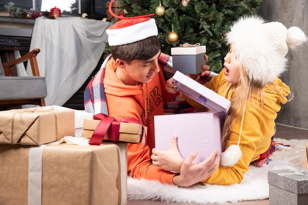 Junges Paar liegt auf dem Boden und öffnet Geschenke