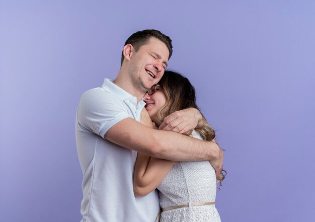 Junges Paar Mann und Frau glücklich in der Liebe, die über Blau umarmt