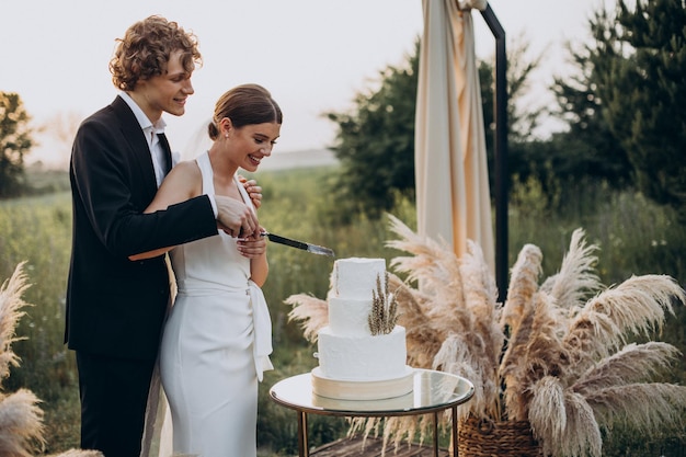 Junges Paar schneidet seine Hochzeitstorte an