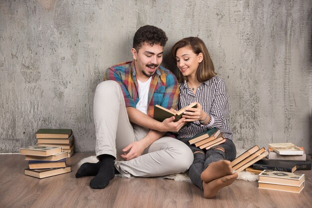 junges Paar sitzt auf dem Boden und liest ein Buch