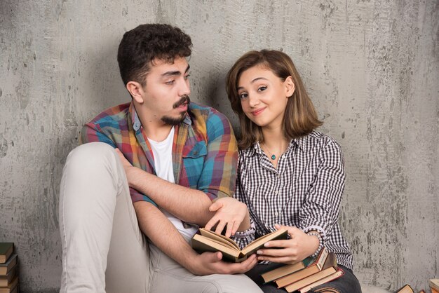 junges Paar sitzt auf dem Boden und liest ein Buch