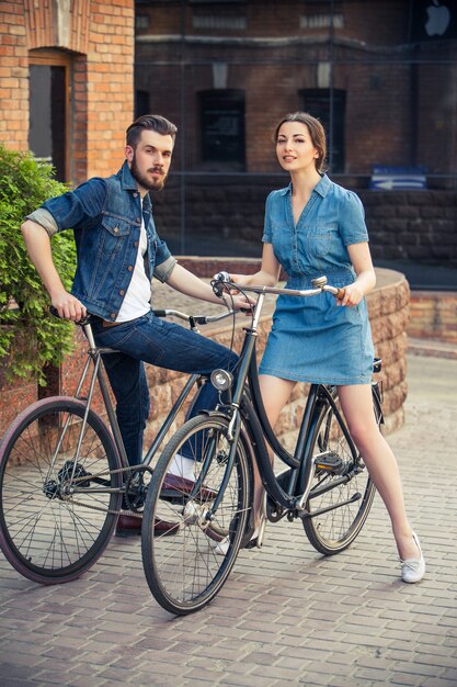 Junges Paar sitzt auf einem Fahrrad gegenüber der Stadt