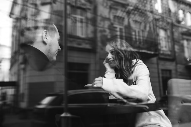 Junges Paar sitzt in einem Café hinter dem Fenster