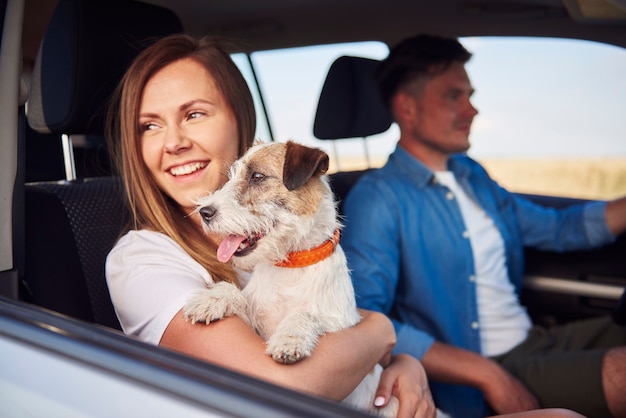 Junges Paar und ihr Hund reisen zusammen in einem Auto