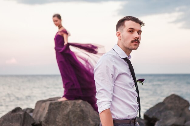 Junges romantisches Paar, das sich am Strand entspannt und den Sonnenuntergang beobachtet