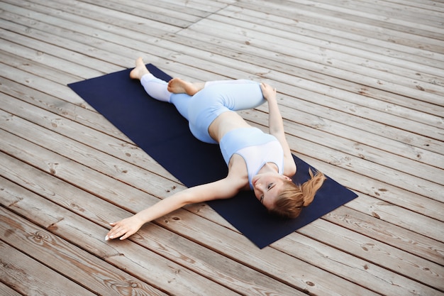 Junges schönes blondes Mädchen, das draußen Yoga praktiziert.