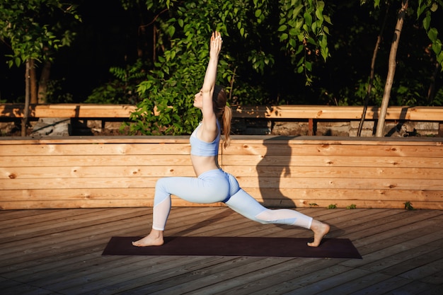 Kostenloses Foto junges schönes blondes mädchen, das yoga draußen bei sonnenaufgang praktiziert.