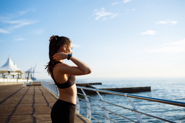 junges schönes Fitnessmädchen macht Sportübungen mit Seeküste an der Wand