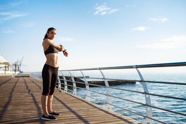 junges schönes Fitnessmädchen macht Sportübungen mit Seeküste an der Wand