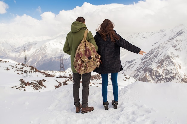 Junges schönes Hipsterpaar, das in den Bergen wandert, Winterferienreisen, Mann Frau in Liebesansicht von hinten