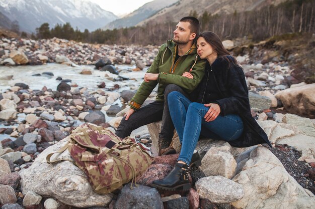 Junges schönes Hipsterpaar verliebt, das durch den Fluss, wilde Natur, Winterferien geht